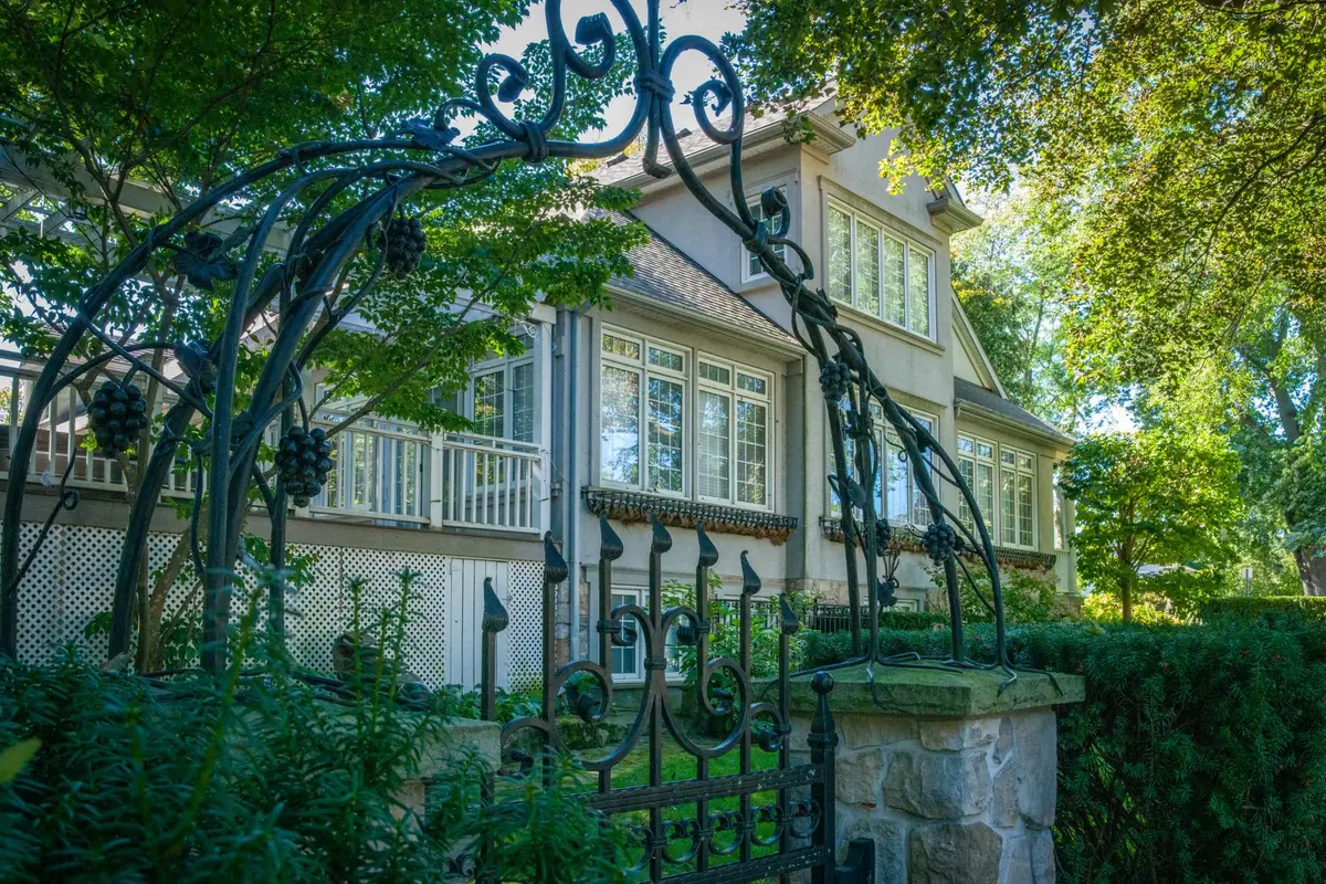 Ornamental black metal gate in front of a well-kept two-story home