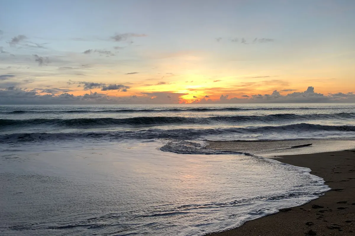 Sunrise over the Atlantic with waves on a wet beach