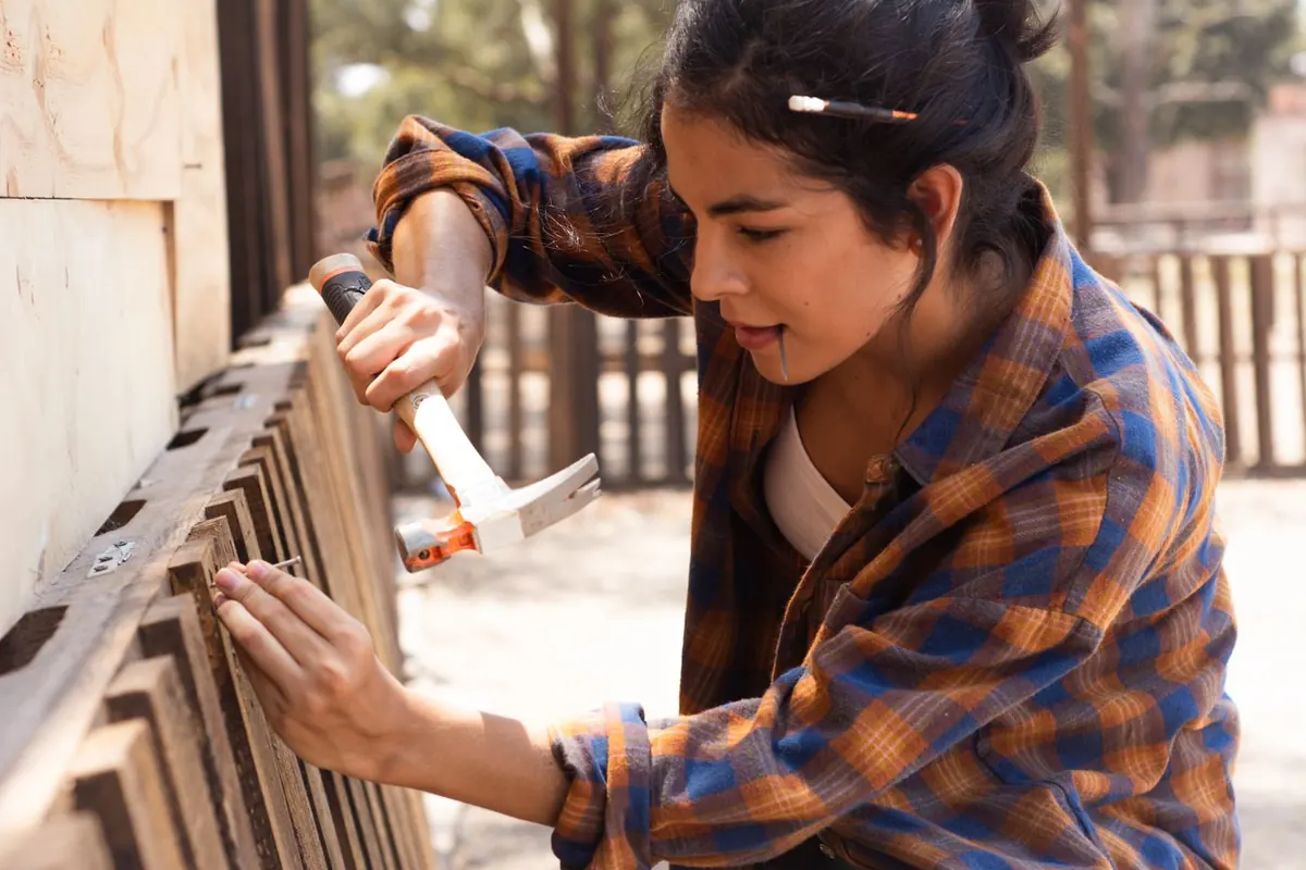 Worker hammering a board back onto a wood fence